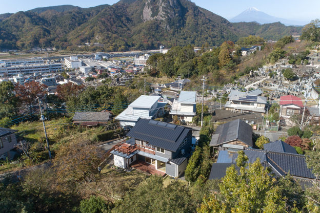 たくさんの木々と山々に囲まれた自然豊かな土地に建つ。晴れた日には二階のデッキから富士山も眺めることができる。